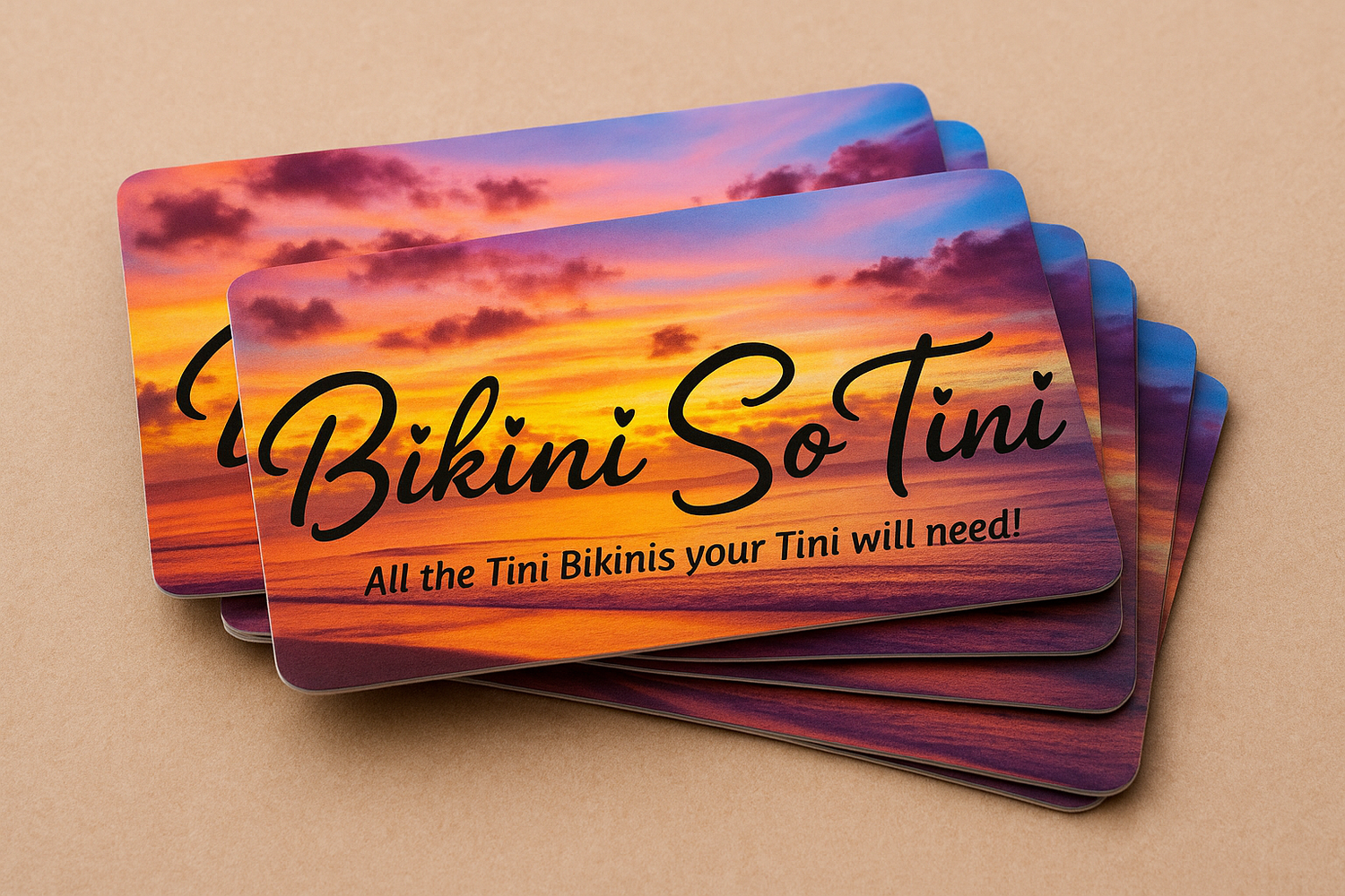 Stack of 'Bikini So Tini' gift cards with sunset design on a beige background